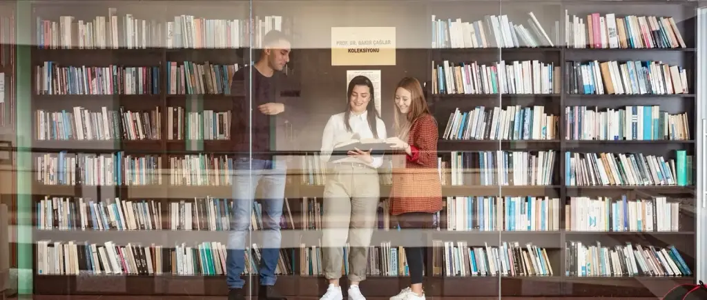 طلاب في مكتبة كلية الحقوق بجامعة شرق البحر المتوسط يتصفحون كتاباً أمام رفوف مجموعة البروفيسور باقر تشاغلار